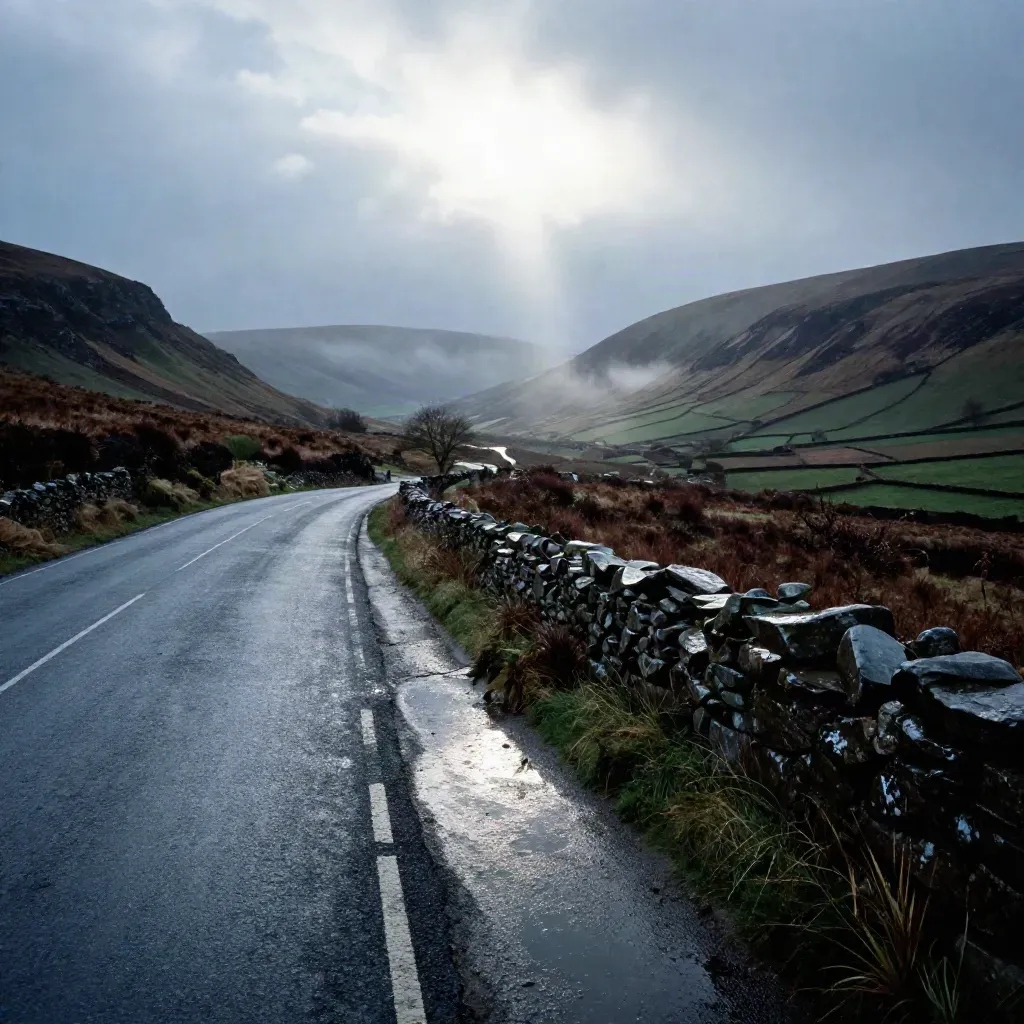 Rain-splashed ridge road above a misty valley with bright cloud break